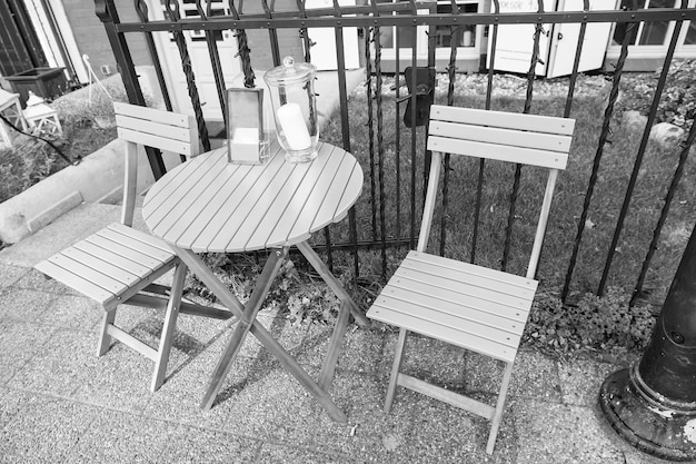 Café en plein air d'été confortable avec bougie sur table et chaises turquoise près de l'herbe verte et clôture de fer avec personne