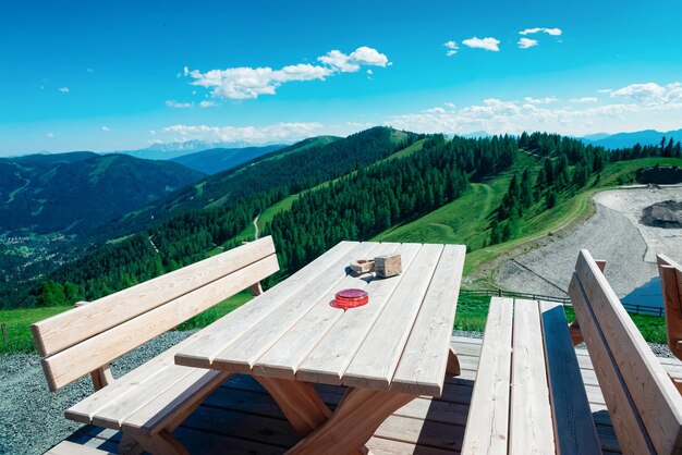 Café en plein air avec tables et chaises en bois dans les montagnes des Alpes et ciel bleu à Bad Kleinkirchheim, Carinthie autrichienne. Collines autrichiennes avec pré vert. Paysage naturel. Voyages et tourisme en été