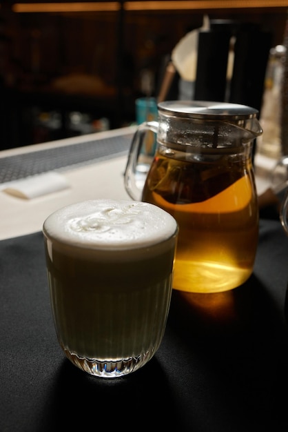 Café une pleine tasse de café avec du lait sur la figure de motif de fleur de table qui a fait avec de la crème