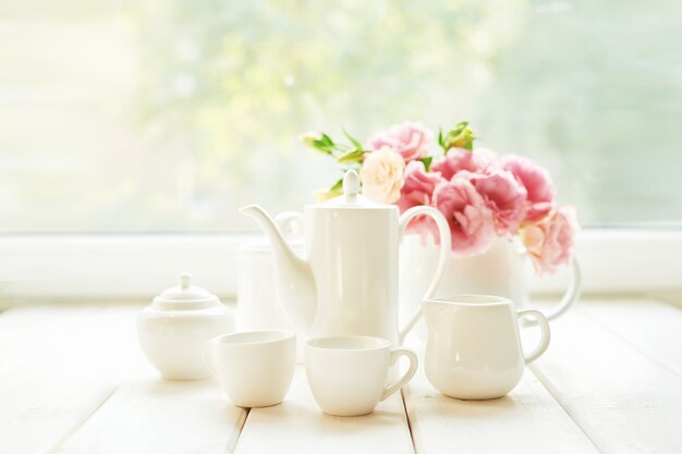 café posé à côté d'un vase de fleurs sur une table contre une fenêtre