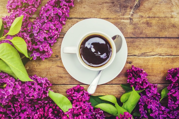 Café pour le petit déjeuner et fleurs lilas. Mise au point sélective.