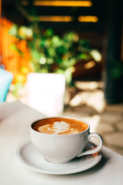 Café savoureux dans une tasse blanche et une assiette sur le tableau blanc