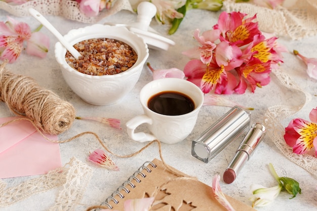 Café et sucre sur un tableau blanc entre les fleurs roses se bouchent