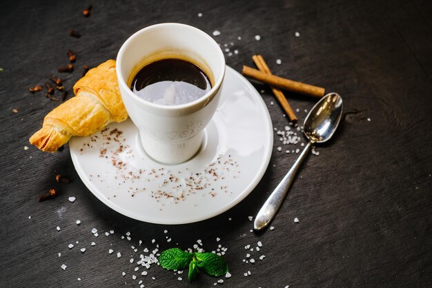 Un café tsty avec croissant sur fond noir