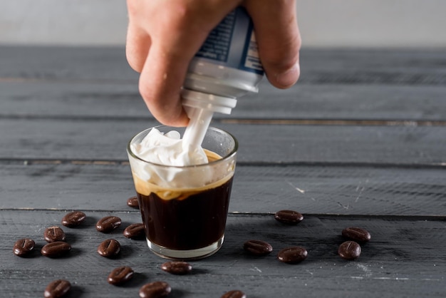 Un café en verre avec de la crème sur le dessus sur fond de bois