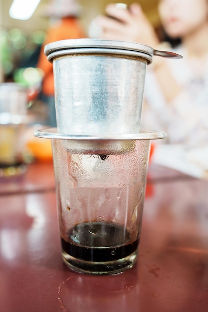 Café vietnamien dans des tasses en verre cafetière traditionnelle en métal phin café goutte à goutte noir aussi célèbre au Vietnam