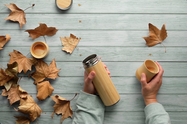 Café zéro déchet dans des tasses en bambou de flacon en métal isolant écologique en automne. Mains tenant le flacon et la tasse.