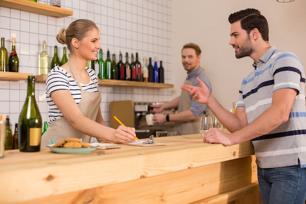 À la cafétéria. Ravi bel homme affamé debout près du comptoir et commander de la nourriture tout en visitant une cafétéria