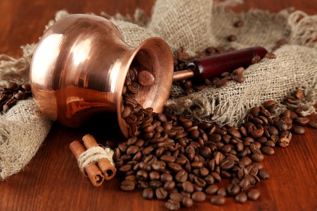 Cafetière avec grains de café sur fond de bois marron