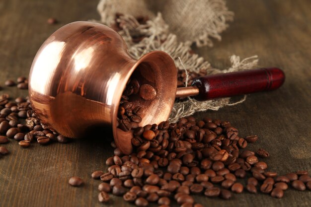 Cafetière avec grains de café sur table en bois