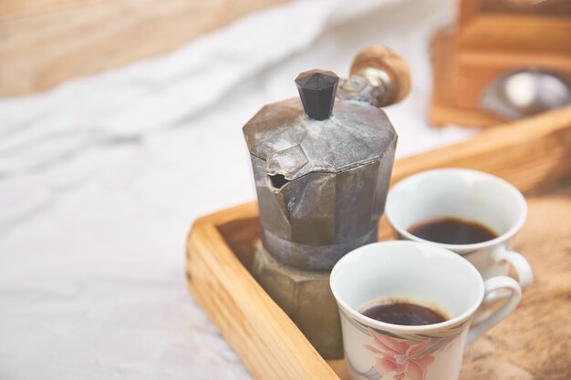 Cafetière Moka avec deux tasses de café sur un plateau en bois