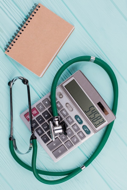 Cahier beige près du stéthoscope et de la calculatrice. Concept de coût des soins de santé.