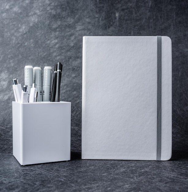 Cahier blanc et groupe de fournitures scolaires avec crayons, marqueurs et stylos
