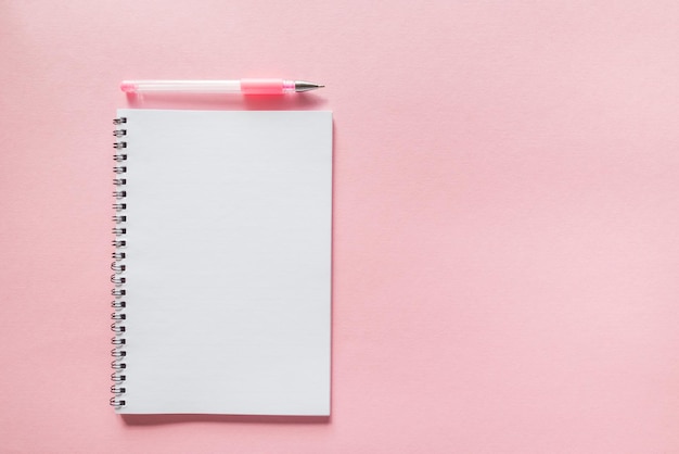 Cahier blanc avec un stylo sur un modèle de mise en page de l'espace de copie de fond rose