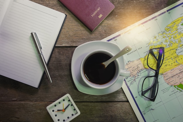 Cahier sur bois rustique avec tasse de café et passeport, horloge et carte