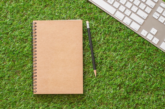 Cahier brun avec un crayon sur fond d&#39;herbe. espace vide pour le réglage