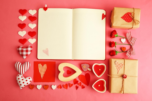 Cahier avec cadeau et décor de la Saint-Valentin sur la vue de dessus de fond rose