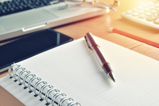 Cahier avec calculatrice, clavier et stylo sur table