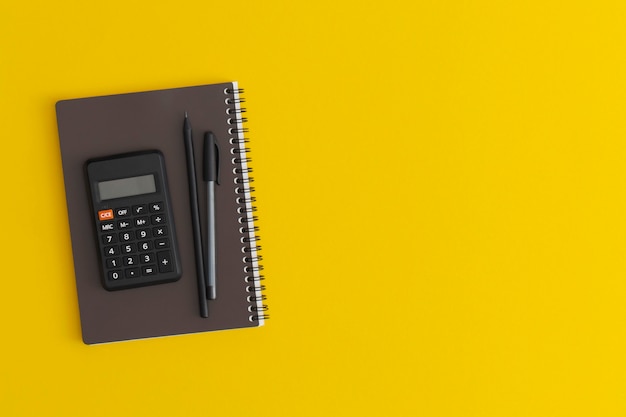 Cahier de calculatrice et stylo sur fond jaune