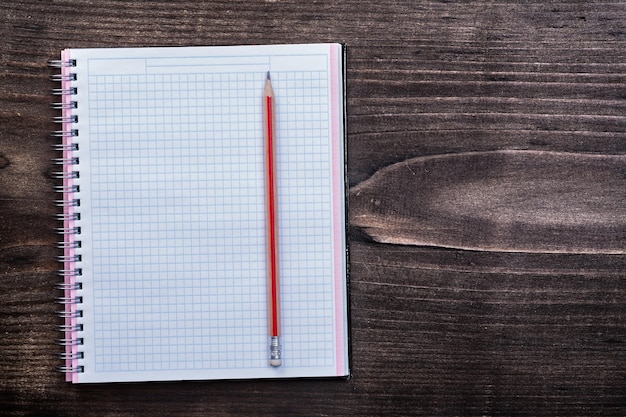 Cahier à carreaux blancs avec un crayon rouge sur le concept d'éducation de planche de bois brun pin