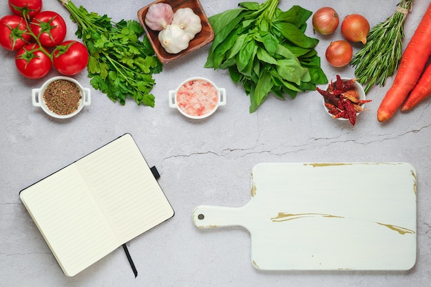 Cahier à côté d'une planche à découper et de légumes frais et d'herbes