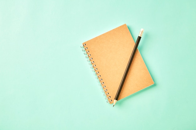 Cahier avec un crayon sur un bureau pastel