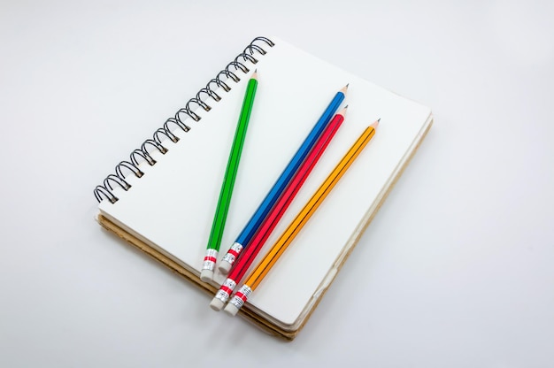 Cahier et crayon coloré sur fond blanc