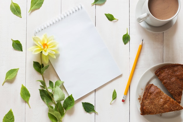 Cahier avec un crayon et des fleurs sur fond en bois