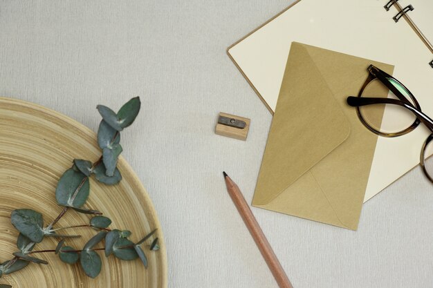 Le cahier, crayon et taille-crayon en bois, enveloppe, lunettes, branches d&#39;eucalyptus dans le panier