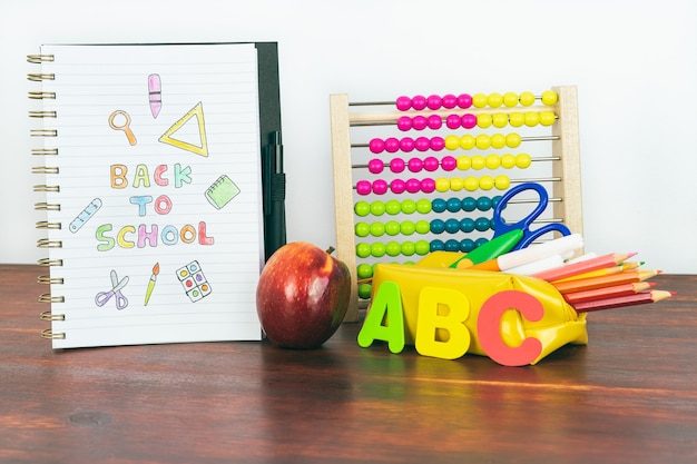 Cahier avec dessin de rentrée. Matériel scolaire avec boulier, crayons, lettres et pomme. Espace de copie