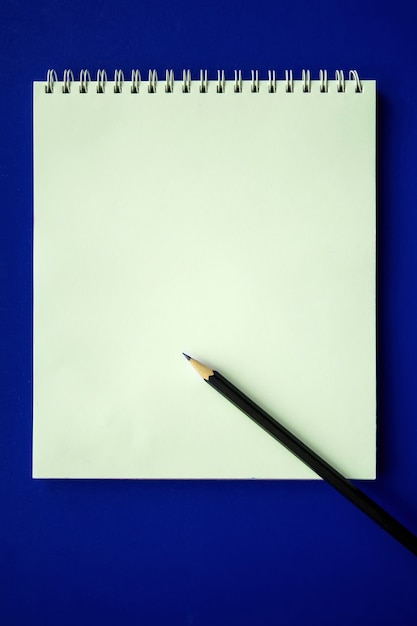 Cahier d'école et crayon sur fond bleu, concept de retour à l'école, éducation élémentaire moderne. mise à plat.