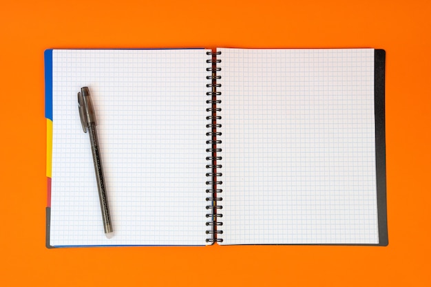 Cahier d'école sous forme ouverte sur une table orange vif Un cahier pour étudier et travailler. Vue de dessus