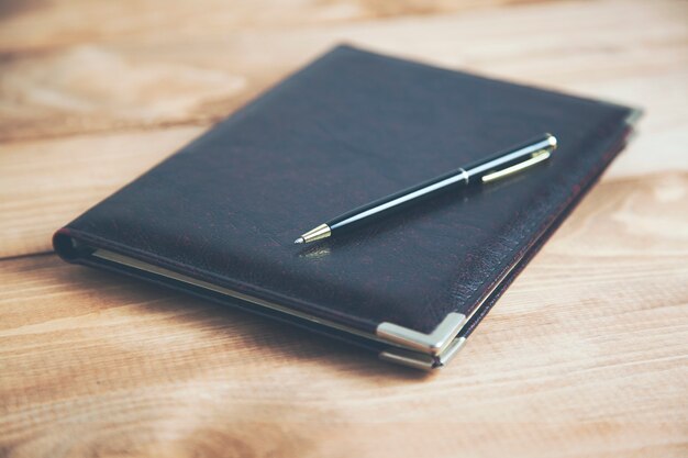 Cahier fermé et stylo sur table en bois