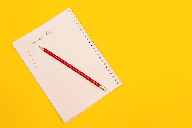 Cahier avec feuille vierge et crayon sur fond jaune