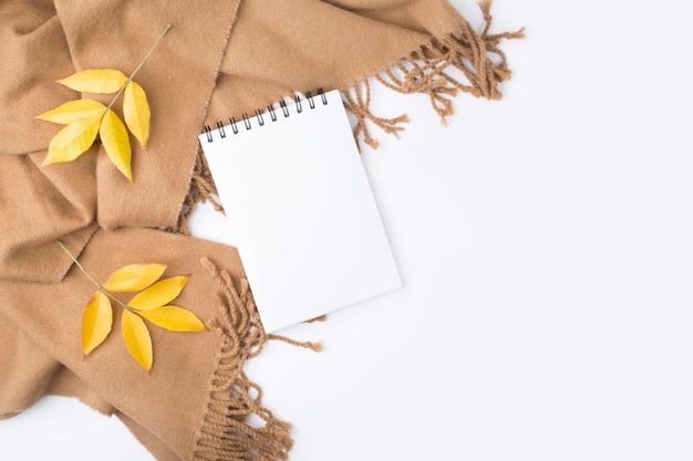 Cahier, feuilles d'automne, plaid sur fond blanc.