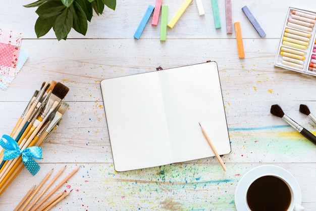 Photo cahier avec des fournitures d'art sur une table en bois blanc