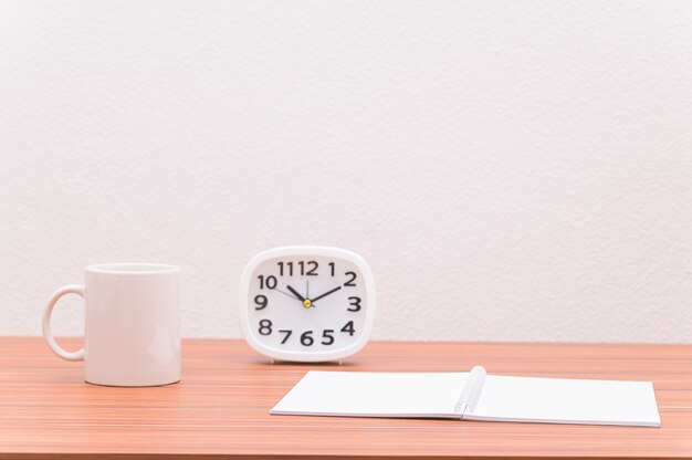 Le cahier et l'horloge sont sur la table.