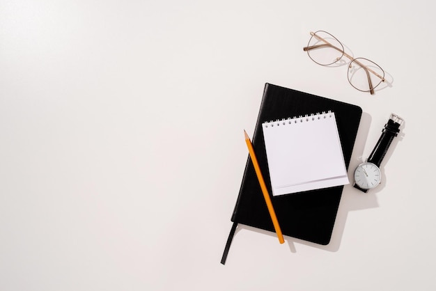 Cahier noir de style minimal et vue de dessus de stylos sur fond vert, superposition d'ombre de palmier