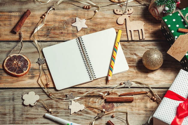 Cahier ouvert et crayon sur table avec des cadeaux de Noël et des décorations