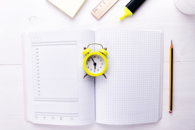 Photo un cahier ouvert avec réveil et fournitures de bureau