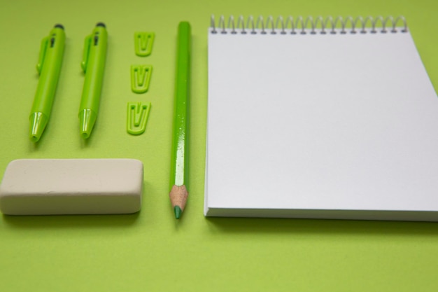 Cahier avec une page vierge sur fond vert pistache et avec un crayon et divers st