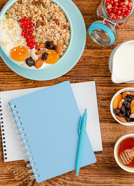 Cahier pour plan de régime et bol granola avec fruits sur bois