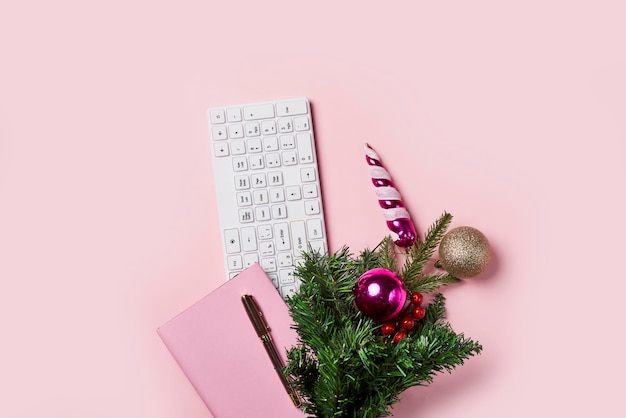 Cahier rose et sapin de noël sur fond rose Bureau plat avec carnet et décoration de noël Travail bureau d'affaires travail à domicile vacances d'hiver concept de carte de voeux