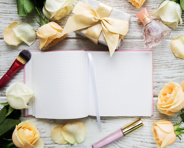 Cahier, roses et cosmétique sur une vieille table en bois