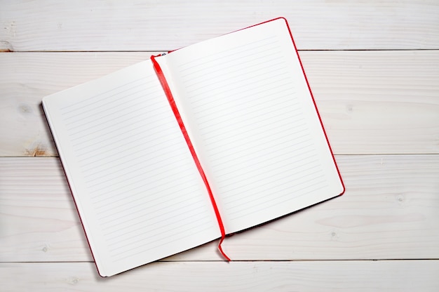 Cahier rouge pour les notes de tous les jours sur une surface en bois blanche