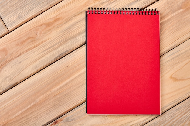 Cahier rouge sur une surface en bois. Bloc-notes en papier en spirale sur la table. Espace pour griffonner.