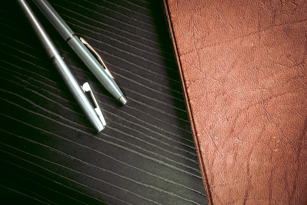 Photo un cahier et un stylo en cuir sur une table en bois