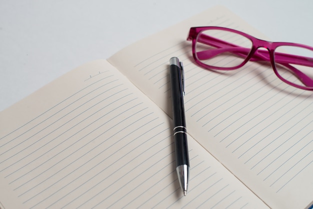Cahier avec stylo noir et lunettes violettes