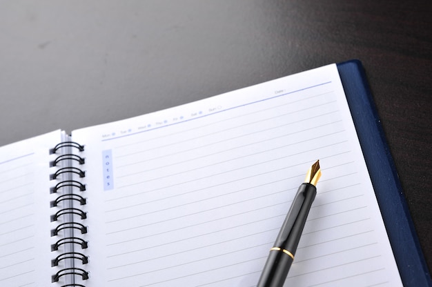 Cahier avec stylo plume sur table en bois