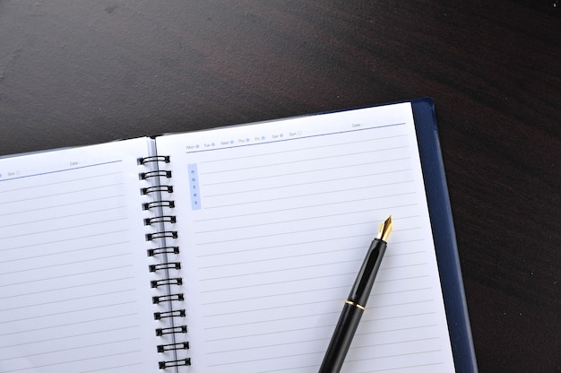 Cahier avec stylo plume sur table en bois